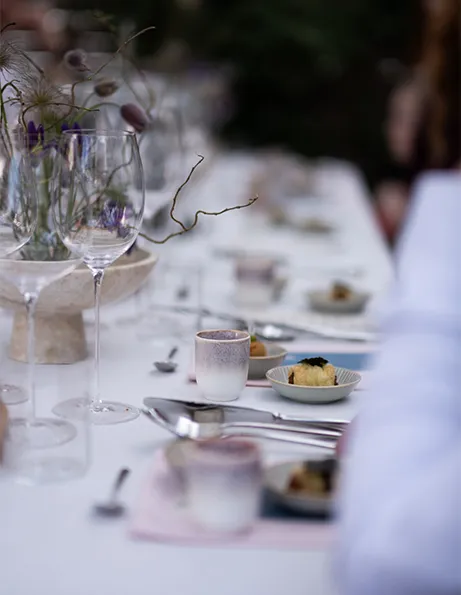 Gedeckter Tisch mit Weingläsern, Besteck, Blumen und kleinen Speiseportione